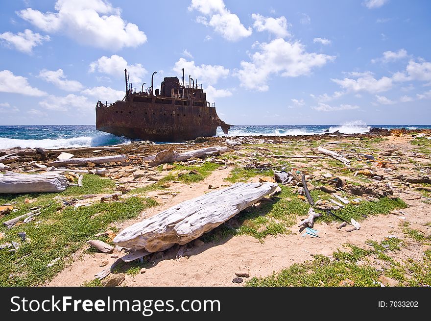Rusty wreck on little curacao with rubbish washed on the shore line. Rusty wreck on little curacao with rubbish washed on the shore line