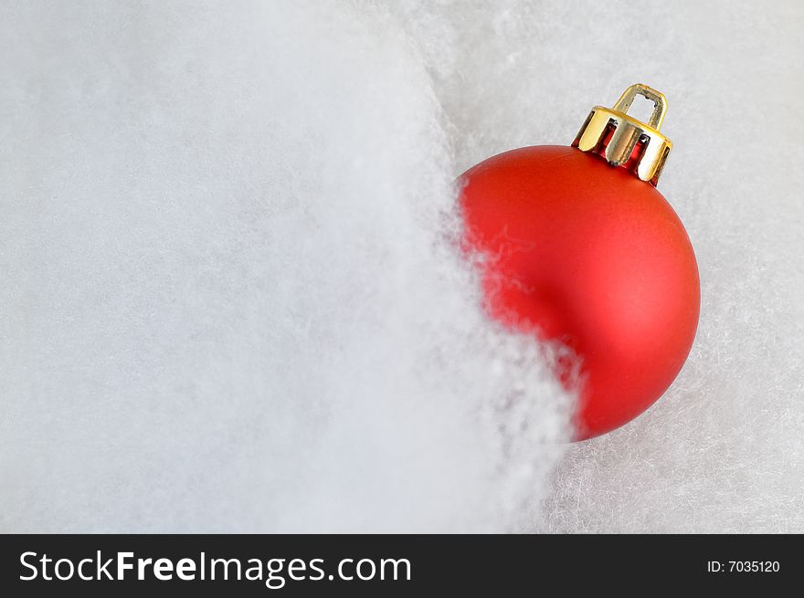 Close up of a red Chrismas bauble in fluffy cotton with copy space and slight glow. Close up of a red Chrismas bauble in fluffy cotton with copy space and slight glow