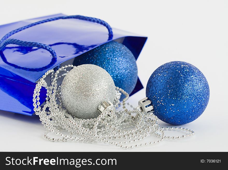 Blue bag, christmas balls and glass beads on white background