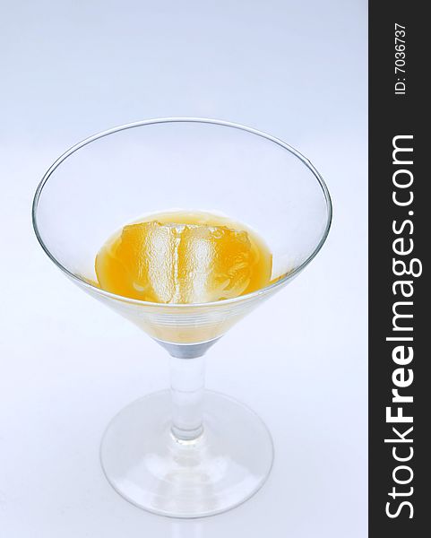 Cocktail glass with mango juice and ice standing on a light blue background. Cocktail glass with mango juice and ice standing on a light blue background