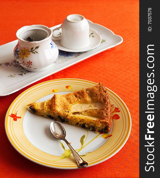 An apple pie in a plate with cups and orange tablecloth. An apple pie in a plate with cups and orange tablecloth.