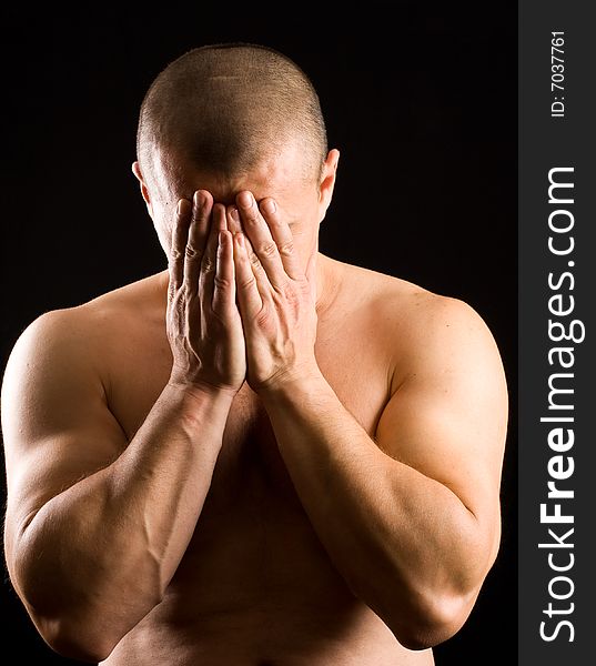 Muscular man covering his face with the hands