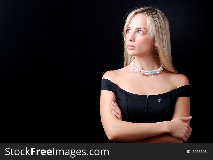 Beautiful young woman in black dress and pearl necklace