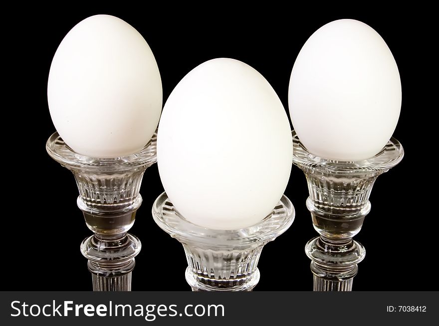 Three eggs on a pedestal, in a triangle formation, on a black background. Three eggs on a pedestal, in a triangle formation, on a black background