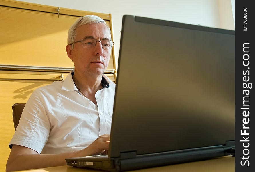 Casual businessman with glasses working on laptop. Casual businessman with glasses working on laptop