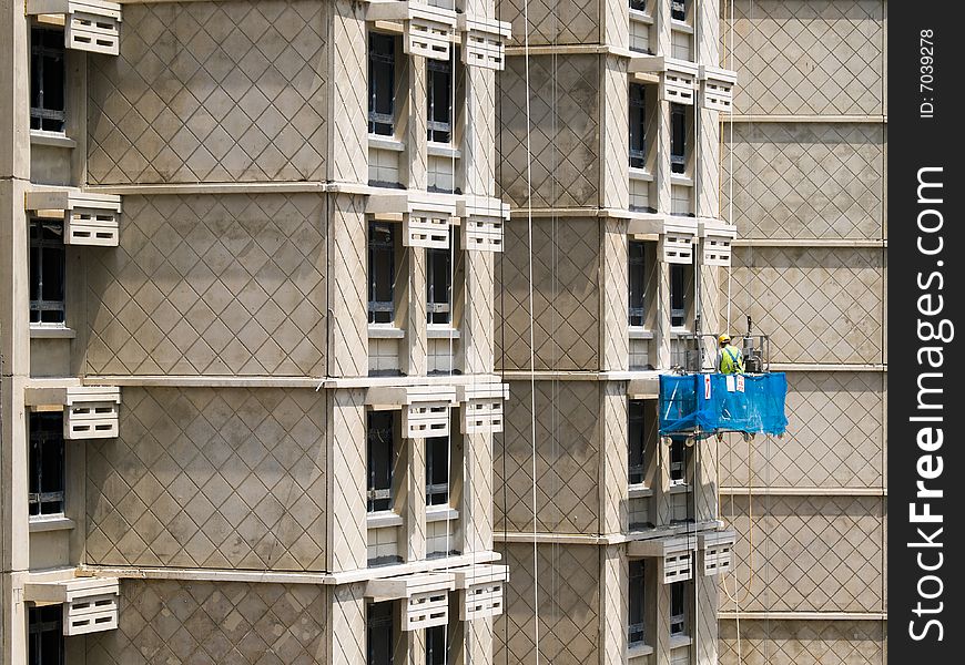 Workers in a lift platform called a gondola working on the exterior of an unfinished apartment block. Workers in a lift platform called a gondola working on the exterior of an unfinished apartment block