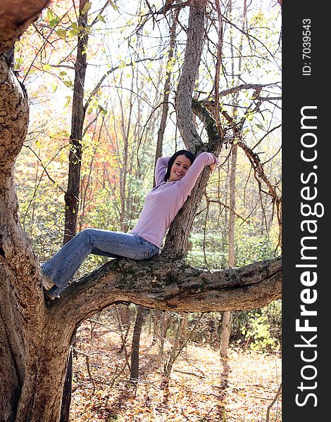 Pretty teen reclining on a large tree branch