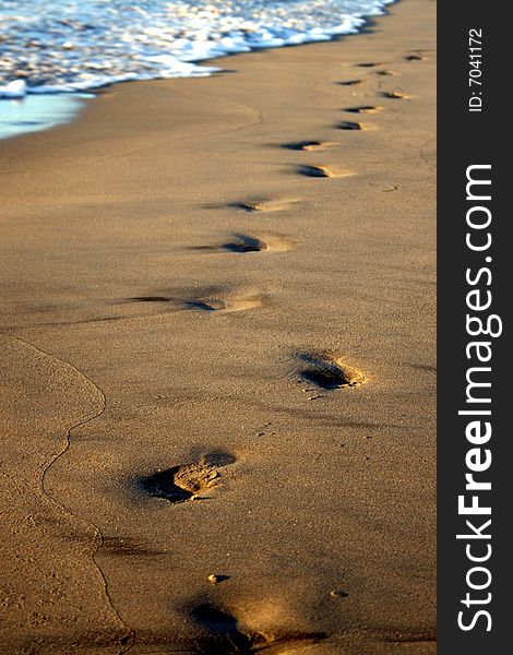 Footsteps on the beach about to be covered by a wave