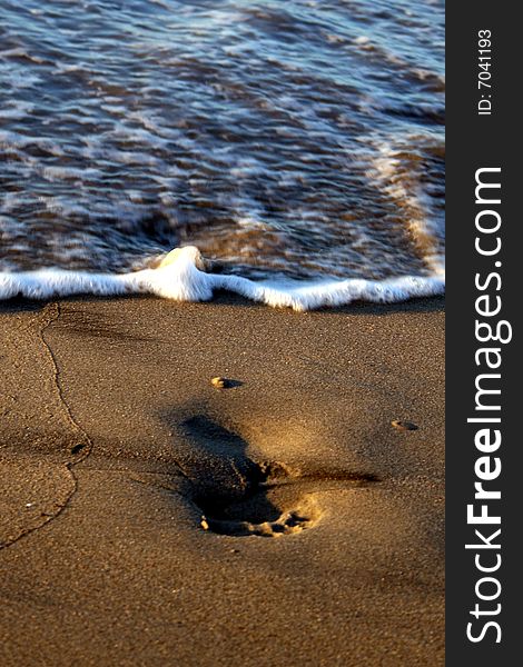 Waves washing away footprints on the beach. Waves washing away footprints on the beach