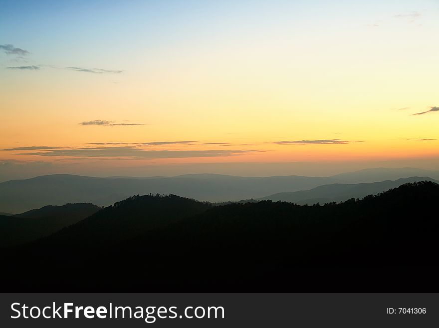 Silhouettes of mountains on background of sunrise