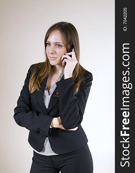 Pretty, young woman, waring a suit, talking over a cellphone. Pretty, young woman, waring a suit, talking over a cellphone