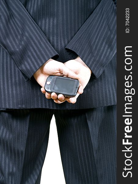 Young businessman in black suit, holding a cellphone behind his back. Young businessman in black suit, holding a cellphone behind his back
