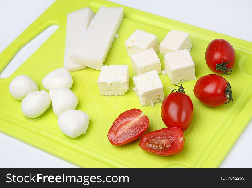 Different cheeses and tomato on cutting board