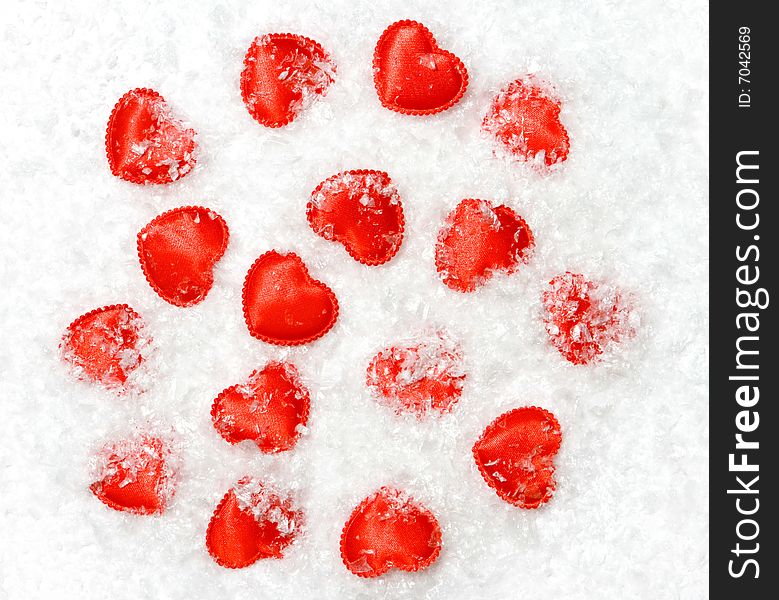 The set of small red hearts lies under snow.