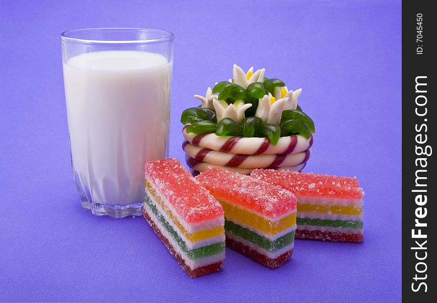 Fruit jellies and milk glass close-up isolated on violet background