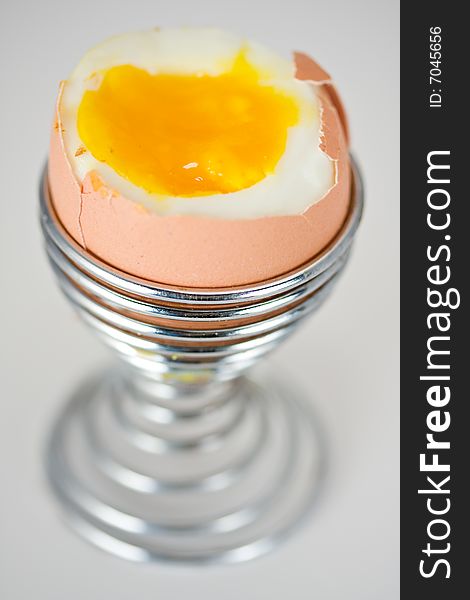 Brown egg in an eggcup on white background