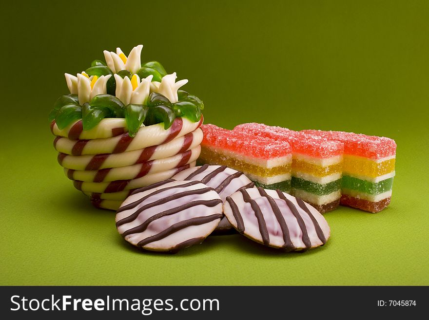 Cakes and fruit jellies close-up isolated on green background