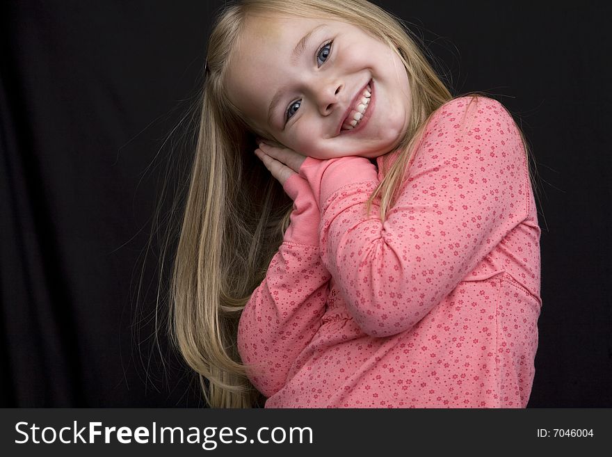 A very happy young girl with her head leaning on her hands. Isolated on black background. A very happy young girl with her head leaning on her hands. Isolated on black background.
