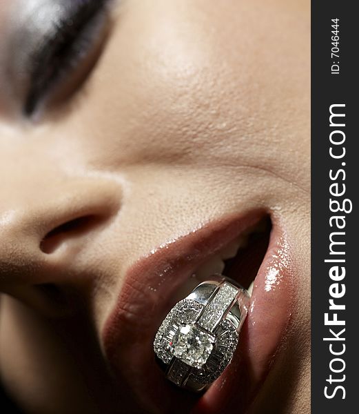 Close up shot of sensual lips holding a diamond ring. Close up shot of sensual lips holding a diamond ring