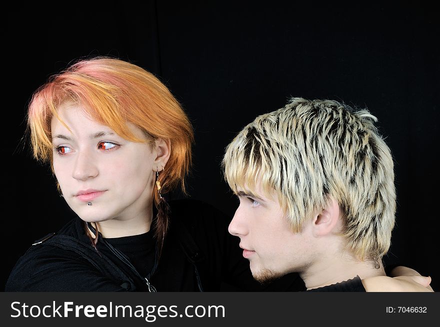 Pretty red-eyed vampire girl and a young guy, on black background