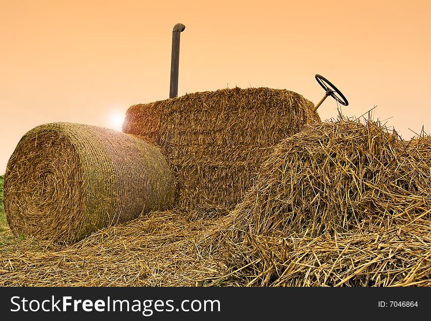 Tractor from bales of straw in fall weather with sunrise