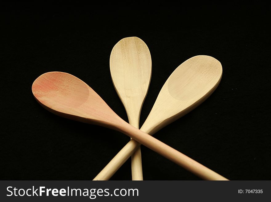 Three wooden spoons crossed on a black background. Three wooden spoons crossed on a black background