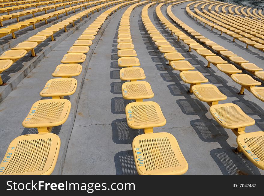 The parallel lines of yellow iron seats in an open stadium. The parallel lines of yellow iron seats in an open stadium.