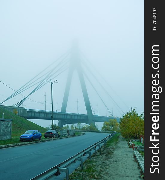 Industrial constructions are in fog, details of bridge are in a grey color