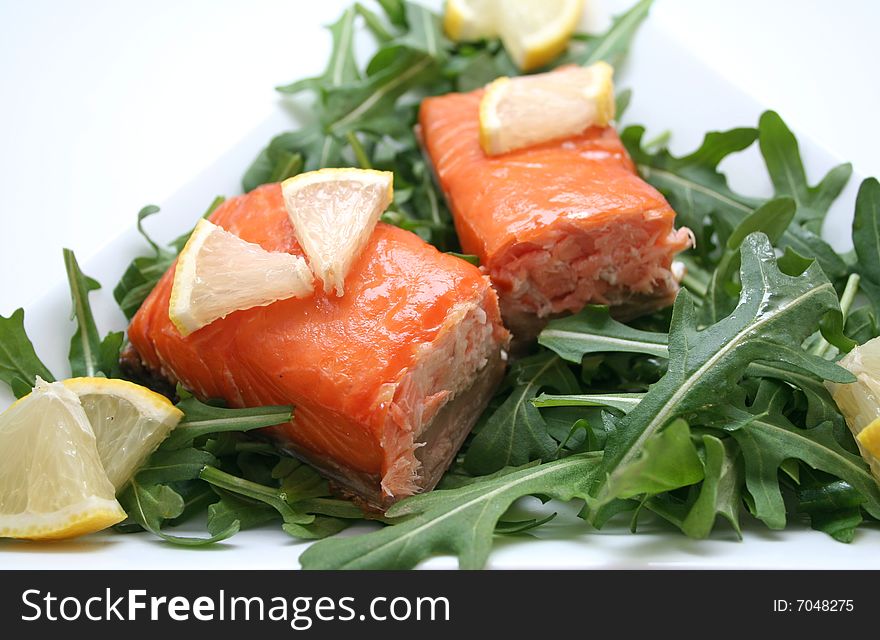 A snack of fresh salmon fish with salad and lemon