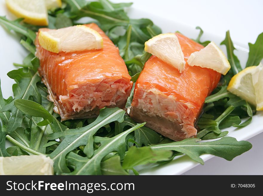 A snack of fresh salmon fish with salad and lemon