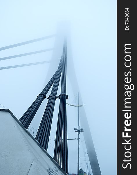 Industrial constructions are in fog, details of bridge are in a grey color