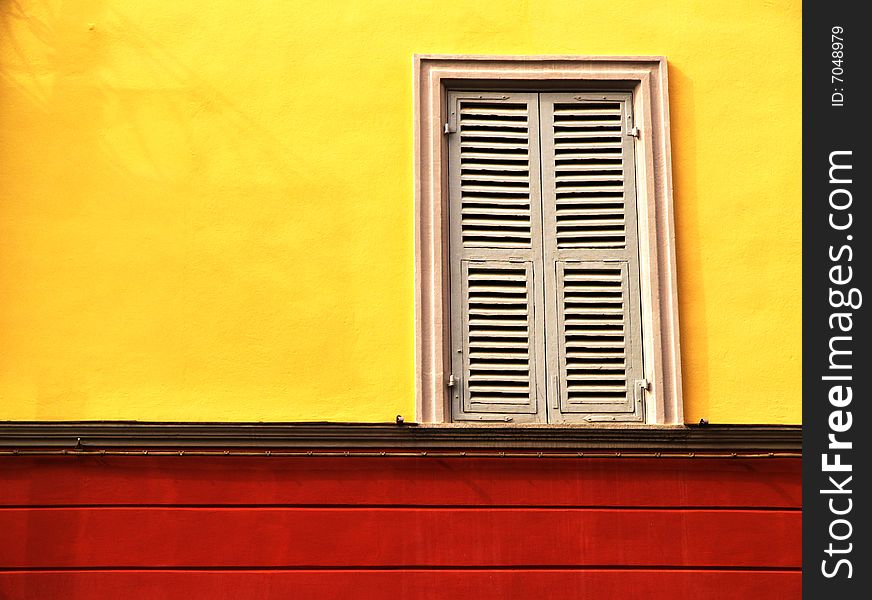 A classic window on a colourful wall dominated by yellow and red.