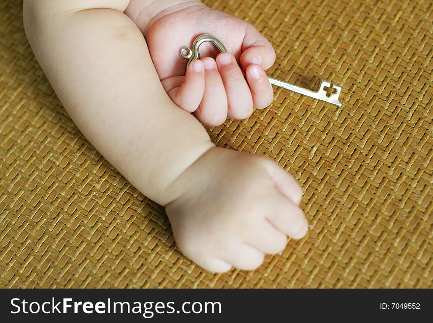 A baby hold gold key lie on bed