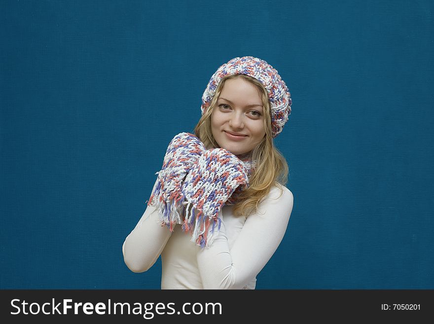 Portrait of a young girl in winter clothes on blue background