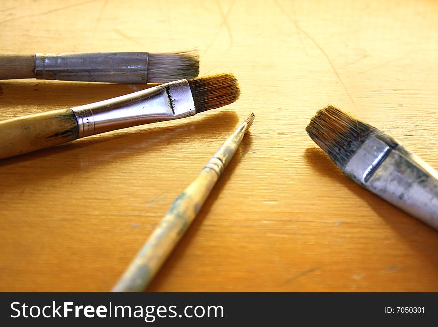 4 artist's paintbrushes on wood