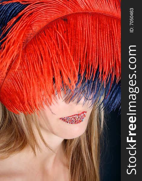 Female model with feathers and hundreds and thousands on her lips.