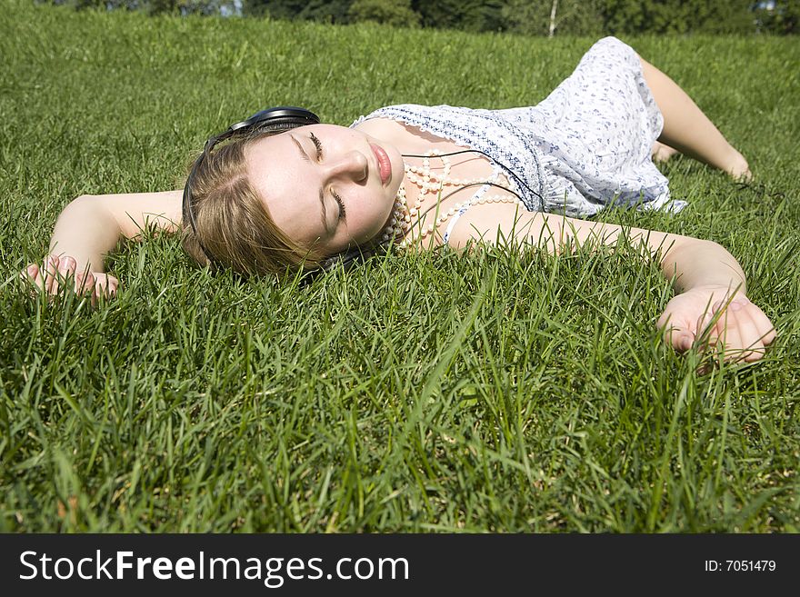 Young woman listening to music lying on grass
