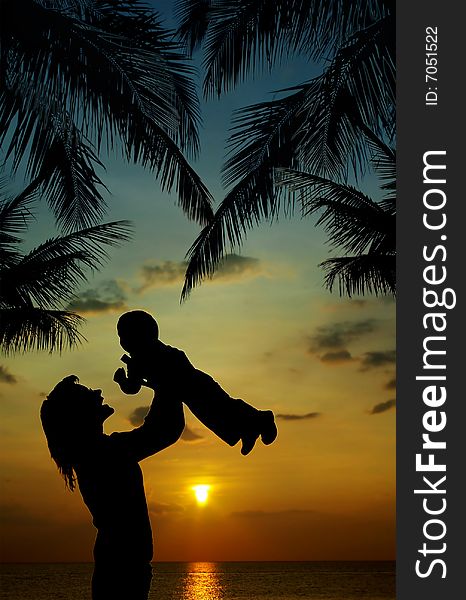 Silhouette of mother and son at sunset in tropics