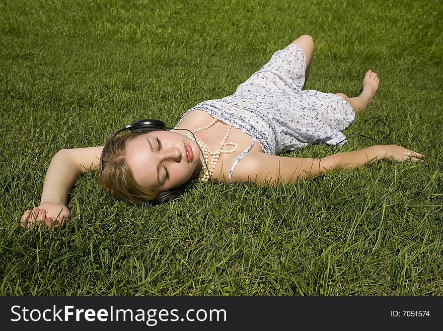 Young woman listening to music lying on grass