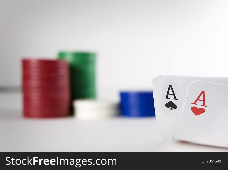 A pair of aces is carefully lifted in front of piles of poker chips. A pair of aces is carefully lifted in front of piles of poker chips