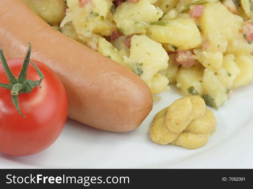 Crisp cooked sausage with potato salad on bright background