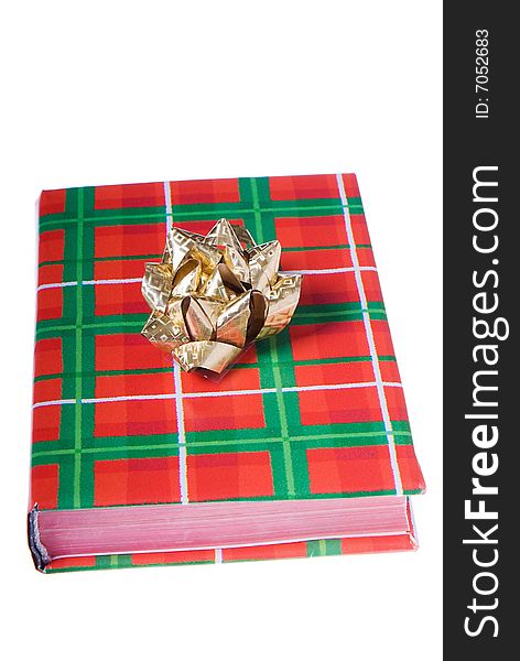 Book wrapped in traditional Christmas colors with golden bow on top. Book wrapped in traditional Christmas colors with golden bow on top