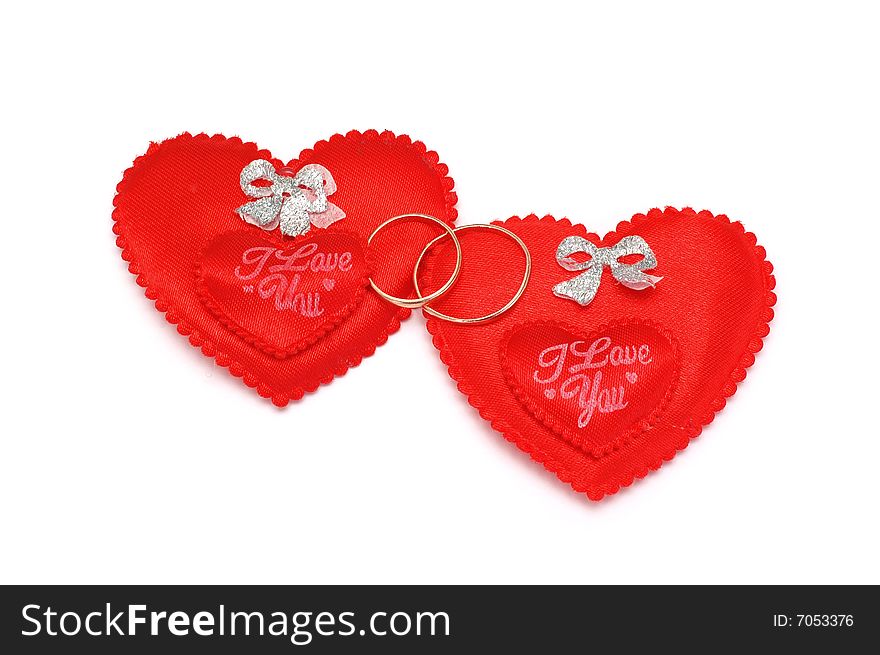 Two red hearts and wedding rings on a white background