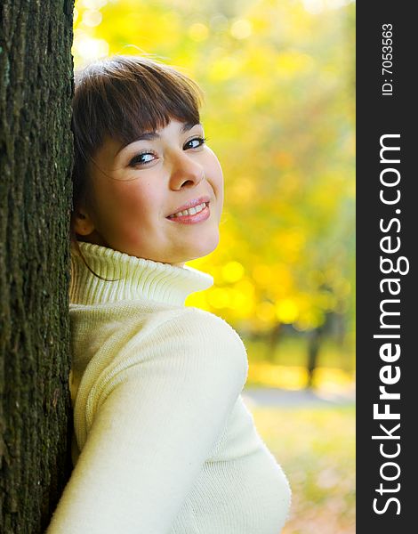 Beautiful girl smiles around tree