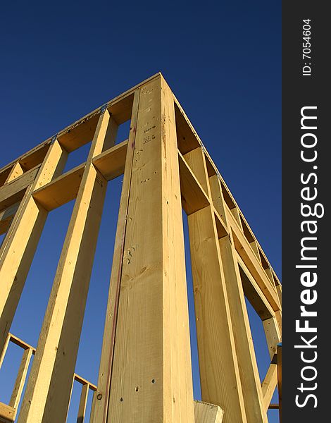 Corner of a framed house against a blue sky. Corner of a framed house against a blue sky.