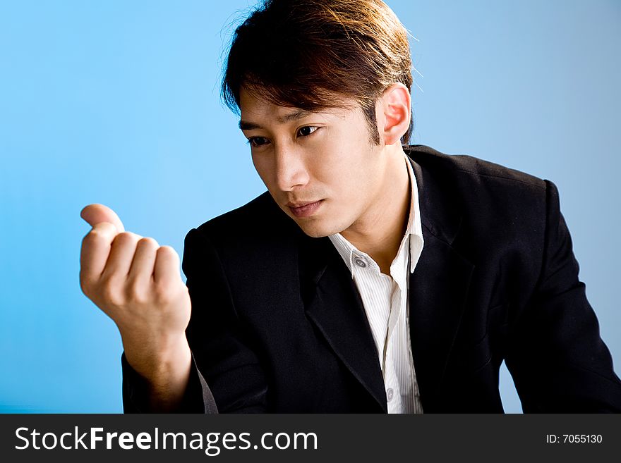 Handsome asian business man looking at his hand in formal attire. Handsome asian business man looking at his hand in formal attire