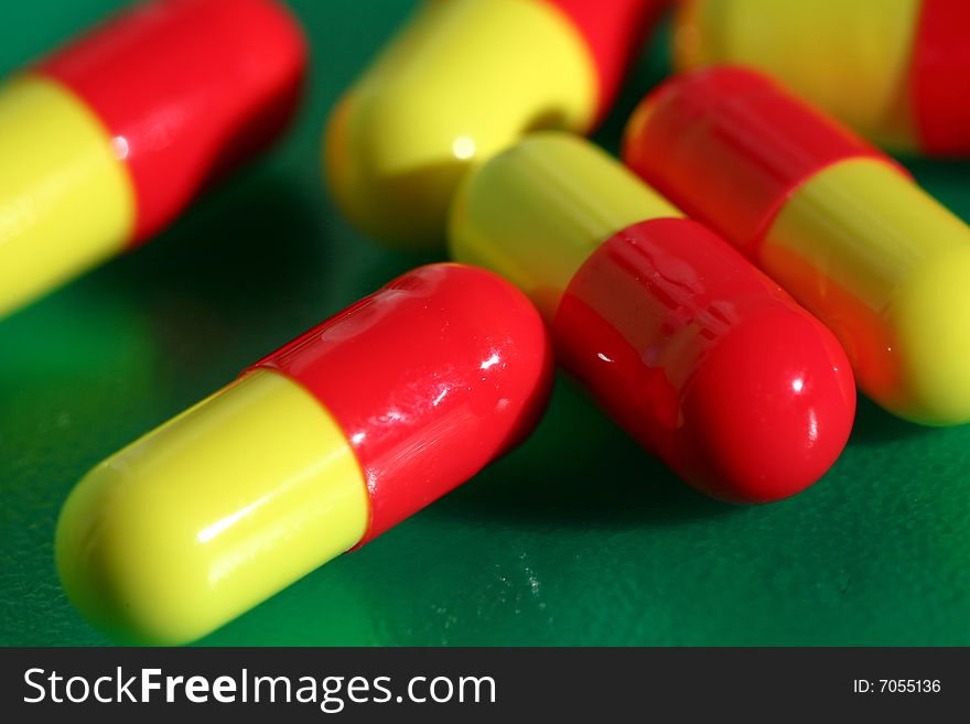 An image of yellow-red pills on green background. An image of yellow-red pills on green background
