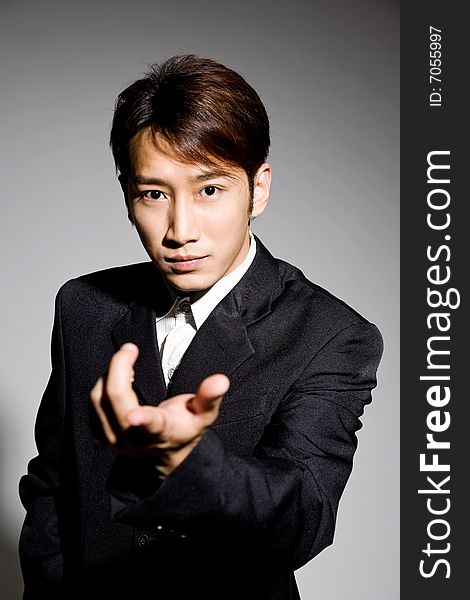 Asian guy in black formal attire coat with hand pointing something