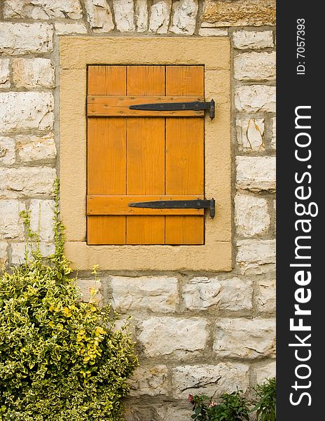 Closeup of window on the stone rural house wall closed with shutter. Closeup of window on the stone rural house wall closed with shutter