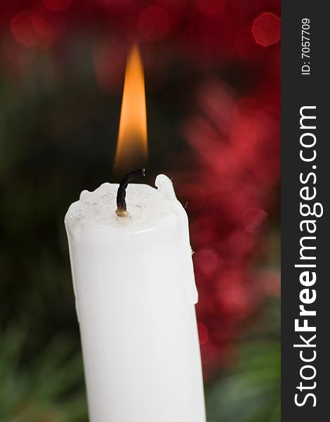 Christmas candle with flame on colored background